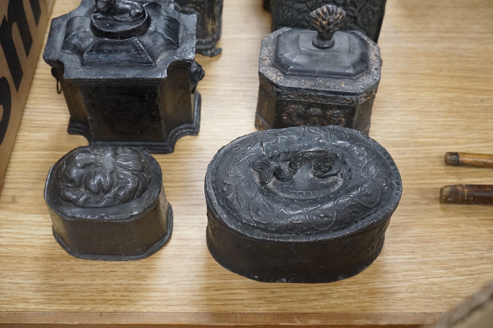 A collection of ten early 19th century lead tobacco boxes, one in the form of a monument with lion knop, largest 14cm wide